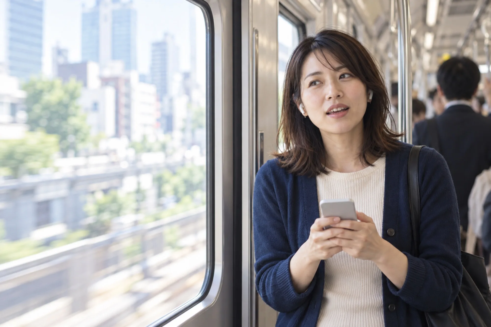 朝の電車の窓辺で、イヤホンで録音を聞きながら英語を小さく口にする女性（写真は見本）